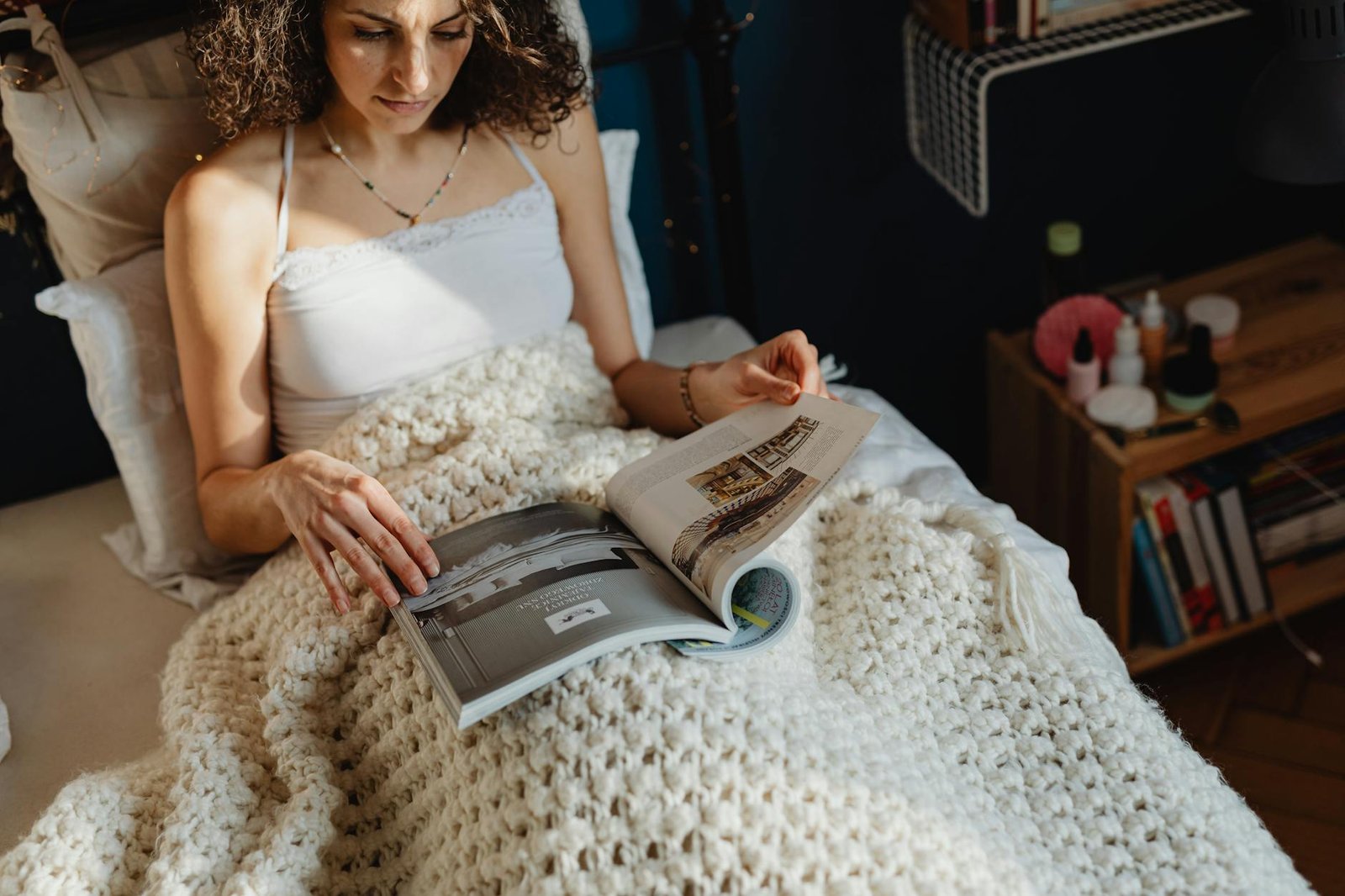 woman looking at a magazine on bed