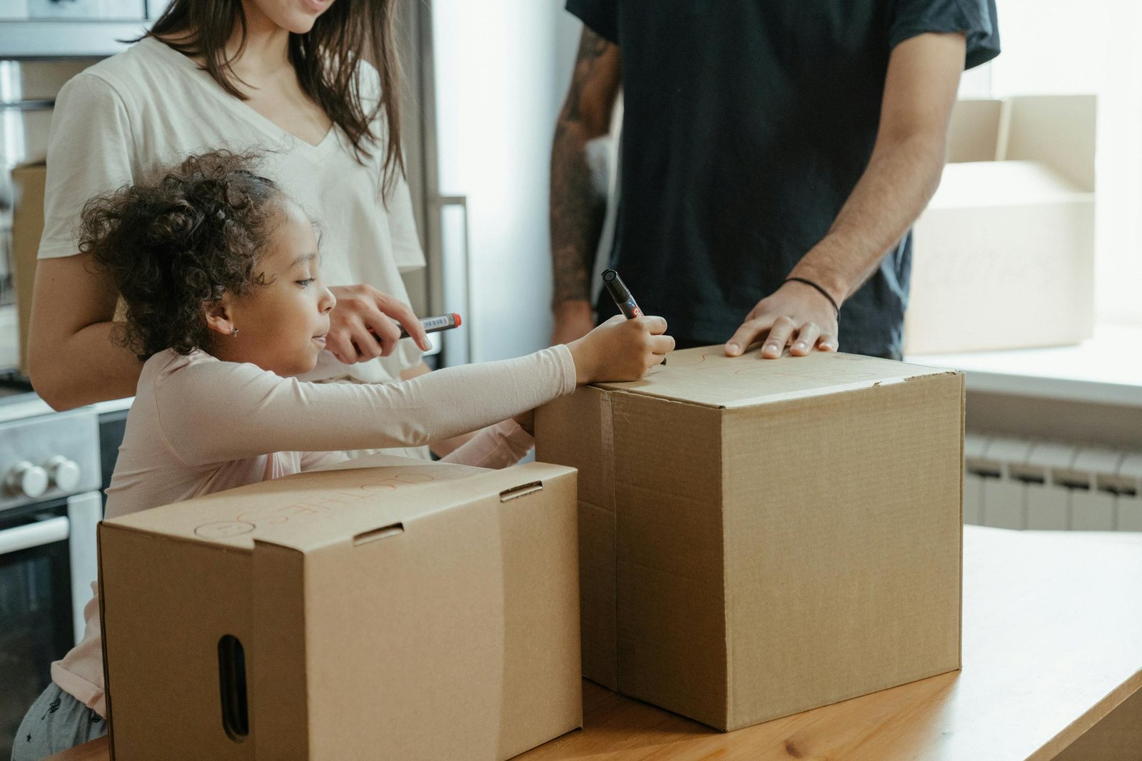 A family labeling moving boxes in their new home, capturing a domestic moment.