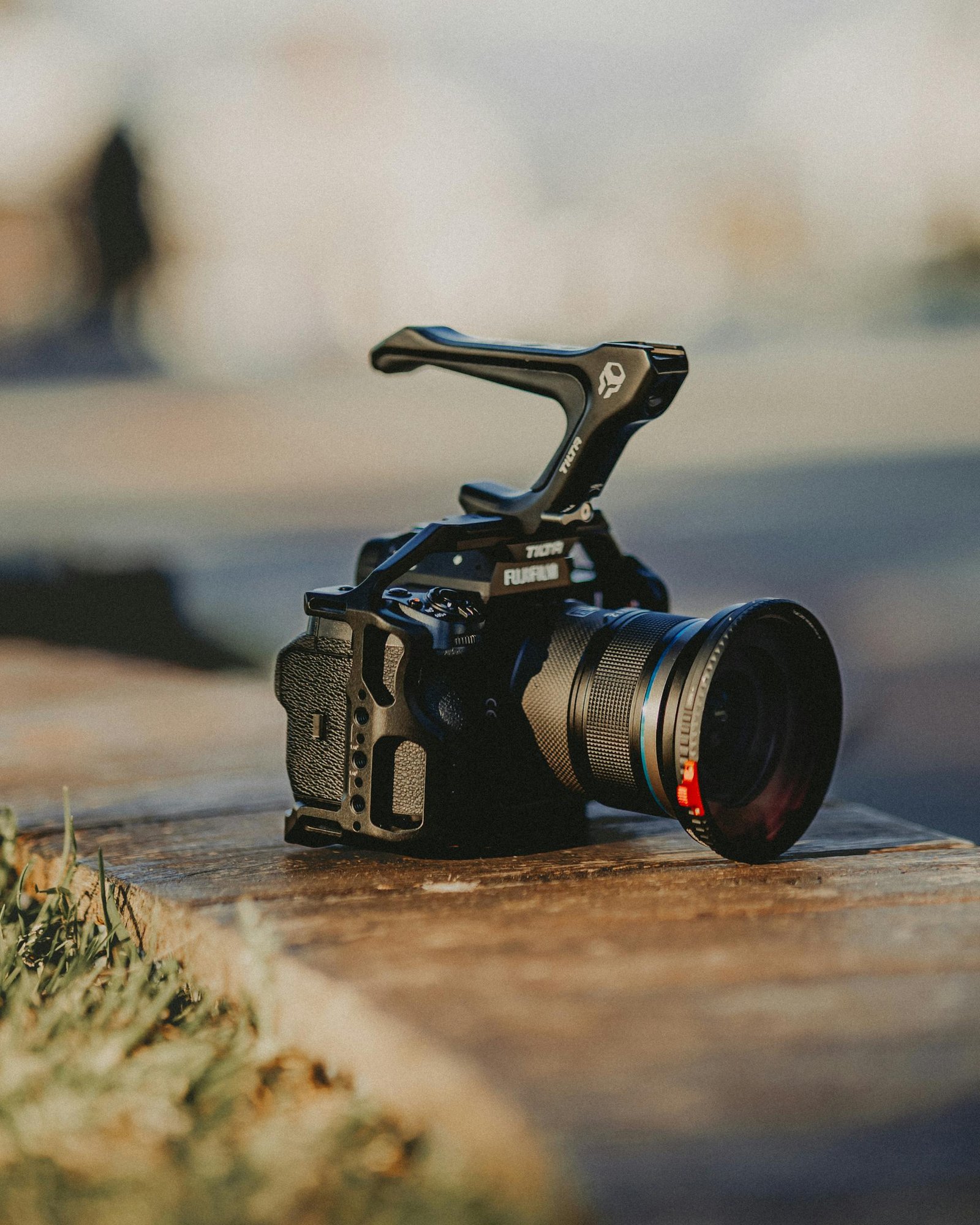 A professional DSLR camera placed on a wooden surface with blurred background.