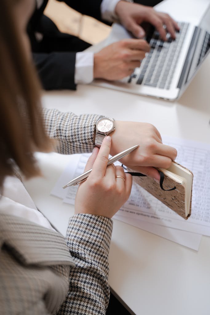 Business professionals at a meeting reviewing notes and checking time.