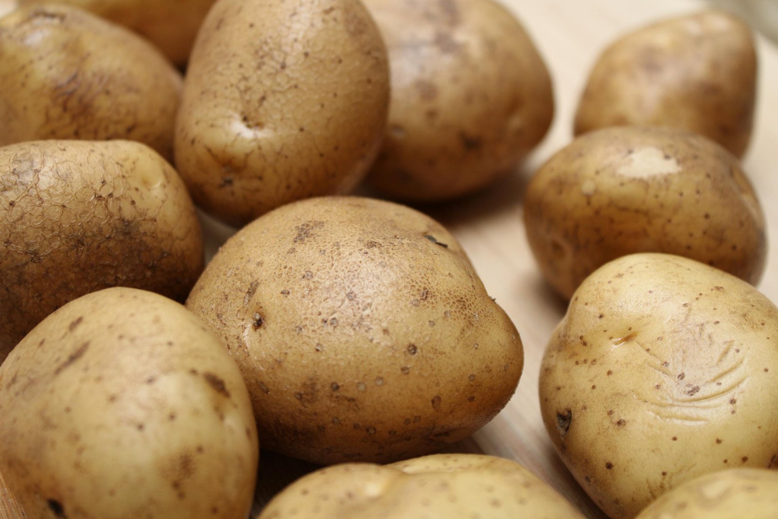 High-quality close-up photo of fresh raw potatoes on a wooden surface, ideal for food and culinary themes.