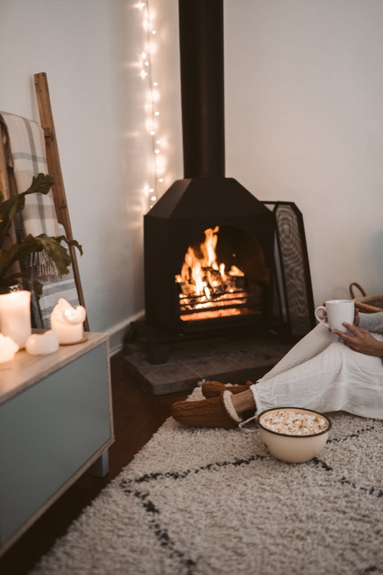Warm and cozy living room setting with a fireplace, candles, and snacks.