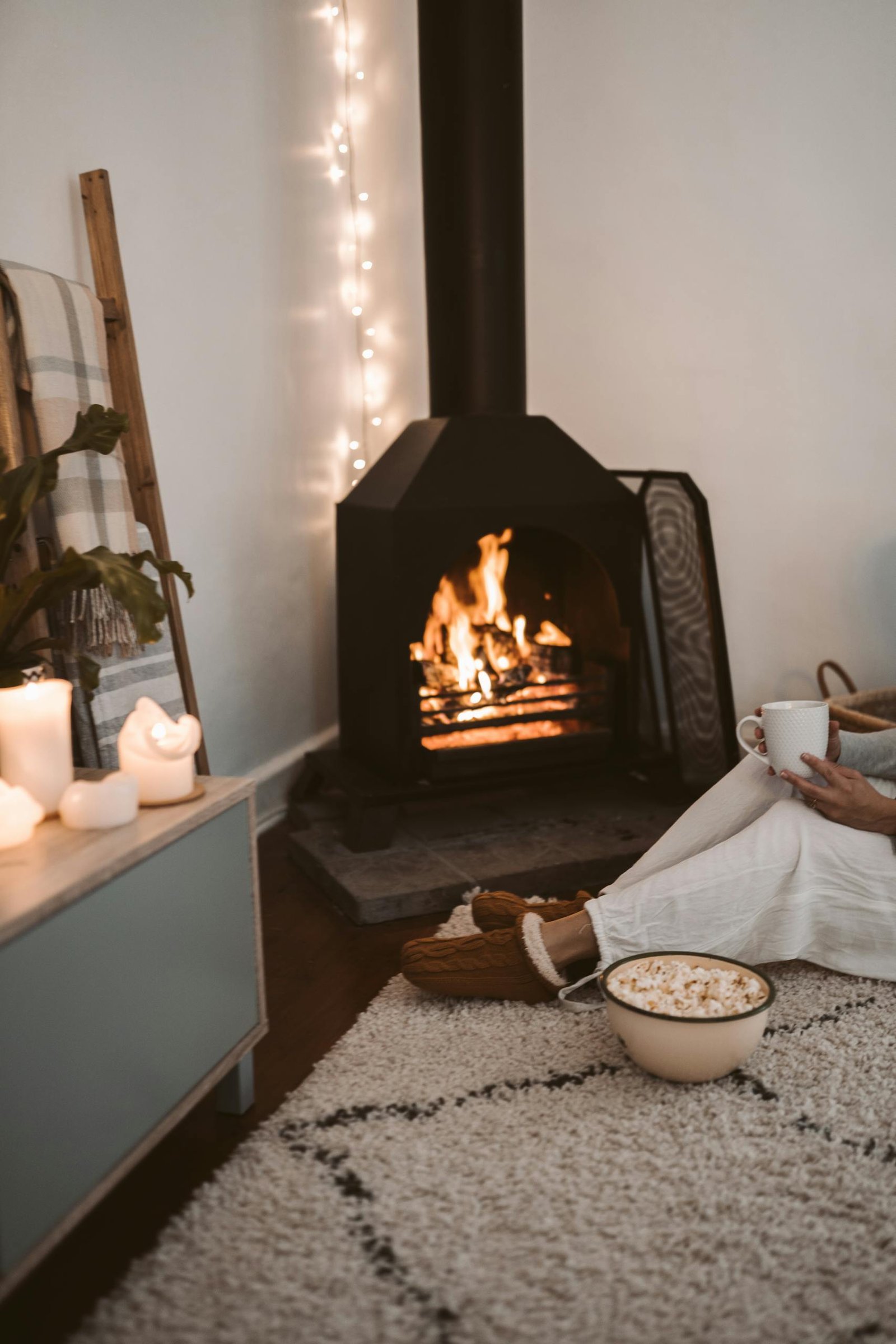 Warm and cozy living room setting with a fireplace, candles, and snacks.