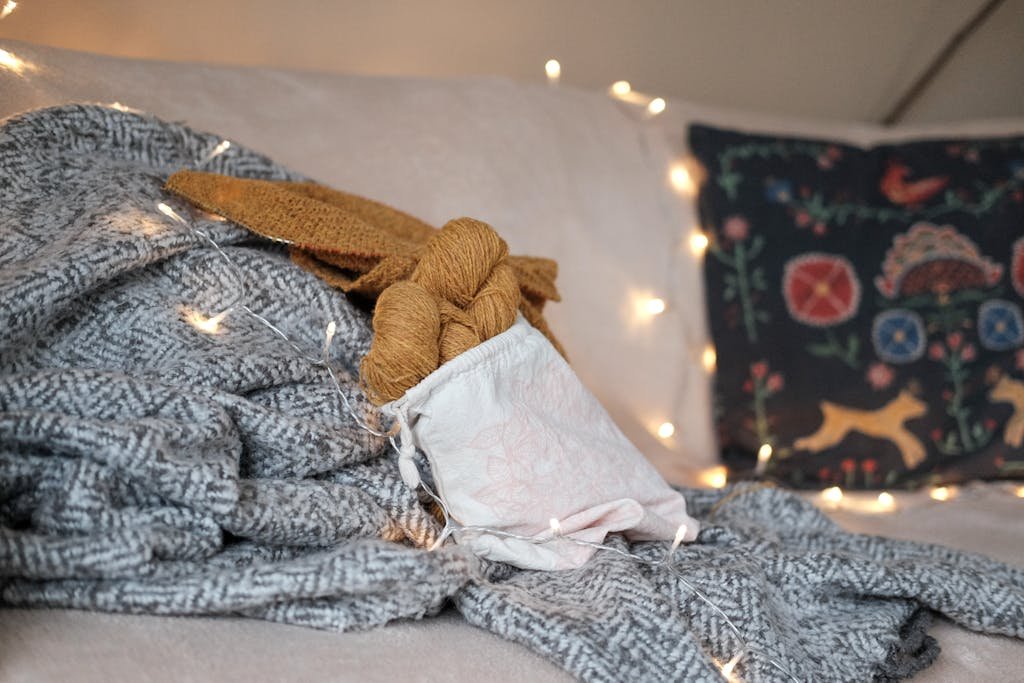 A cozy indoor setup featuring knitted textiles and warm string lights, creating a relaxing winter atmosphere.
