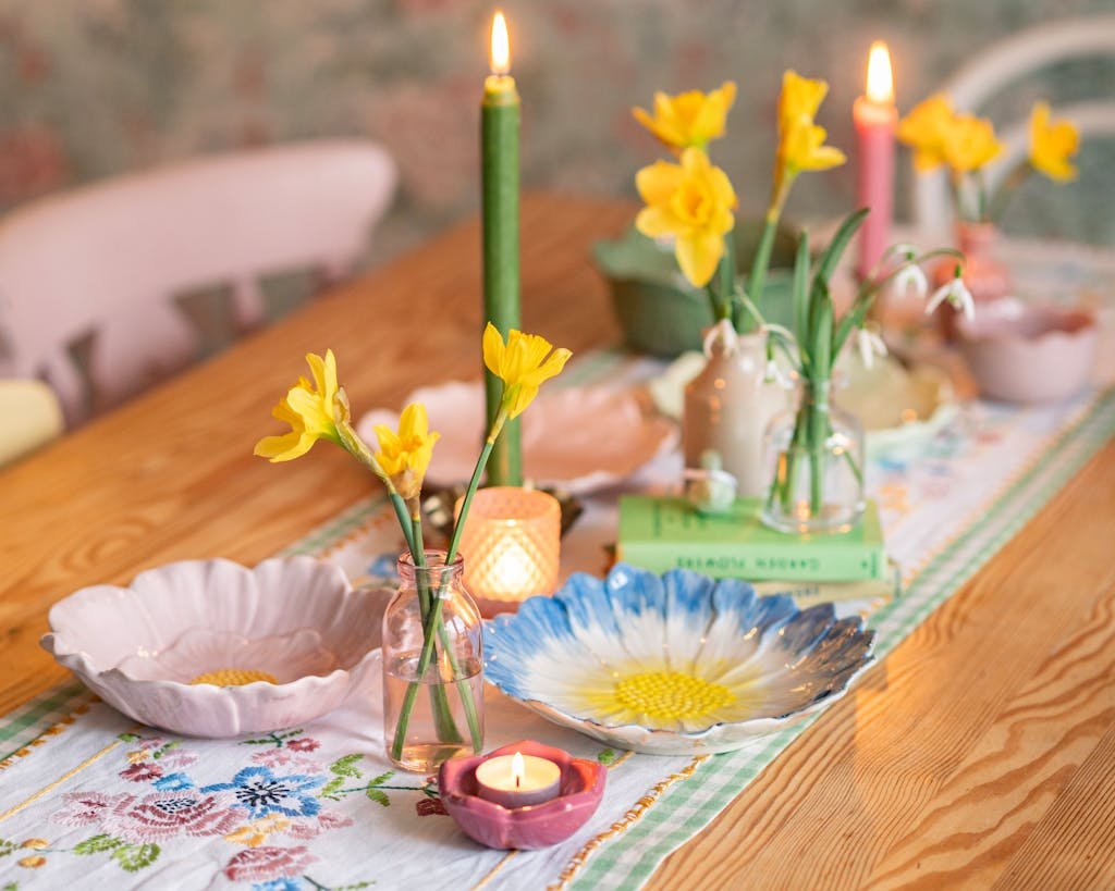 Inviting spring tablescape featuring daffodils, candles, and decorative plates on a colorful runner.