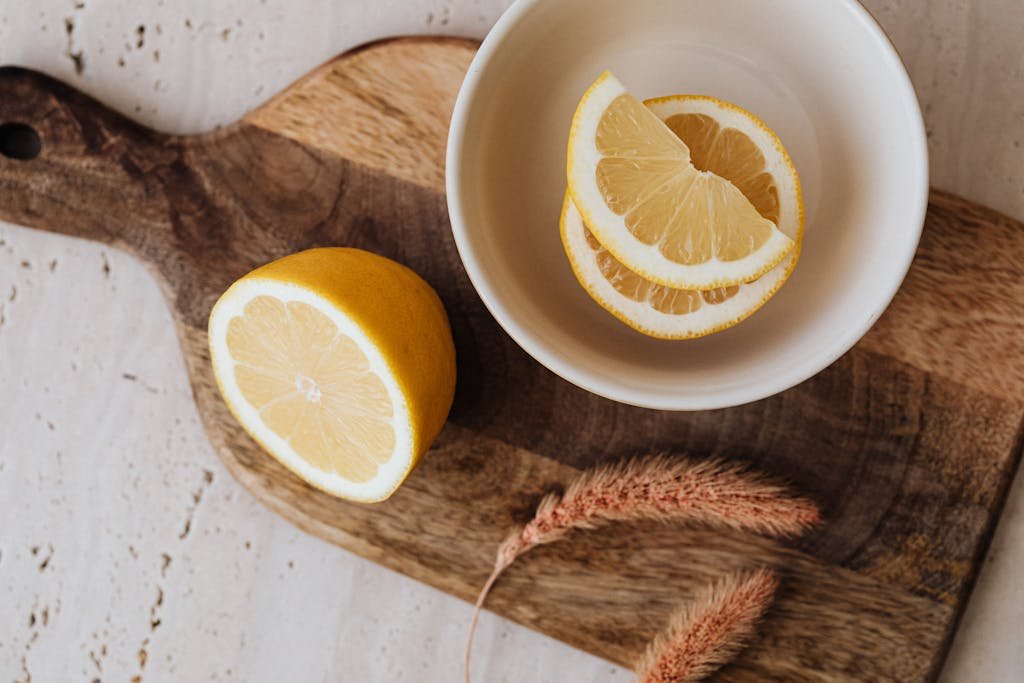 Top view of fresh lemon slices in a bowl on a wooden board, enhancing kitchen decor.